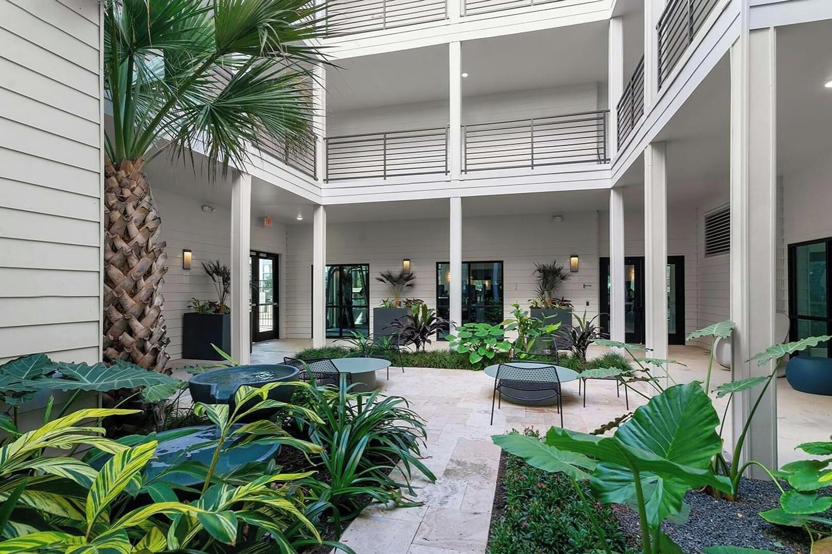 Une terrasse extérieure à plusieurs niveaux, aménagée avec des sièges, des plantes et un palmier.
