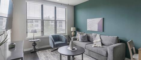 A modern living room with a grey sofa, a round coffee table, and a ceiling fan.