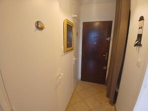 A narrow hallway with a door at the end, a wall-mounted light switch, and a doorbell. - 30m from ski slopes, Ground floor, tv, ski locker, 37m², Alpe d'Huez (L'Alpe d'Huez)