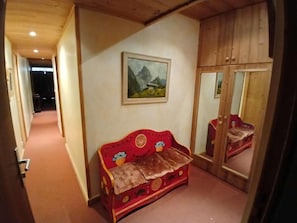 A narrow hallway with a red sofa and a painting on the wall. - 20m from ski slopes, 1st floor, terrace, tv, ski locker, 70m², Alpe d'Huez (L'Alpe d'Huez)