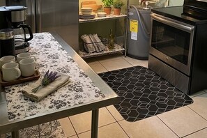 Eine Küche mit Kaffeemaschine, Spüle, Herd und einer gefliesten Spritzschutzwand.