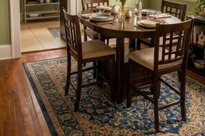 A round dining table with chairs, a rug, and a shelf with dishes in the background. - Cozy 2-bedroom bungalow with AC in charming Jacksonville (Jacksonville)