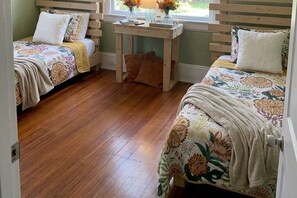 A bedroom with two beds, a wooden table, and a window. - Cozy 2-bedroom bungalow with AC in charming Jacksonville (Jacksonville)