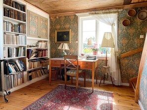 Une pièce avec un bureau en bois, des étagères à livres, un tapis à motifs et une fenêtre avec des rideaux.