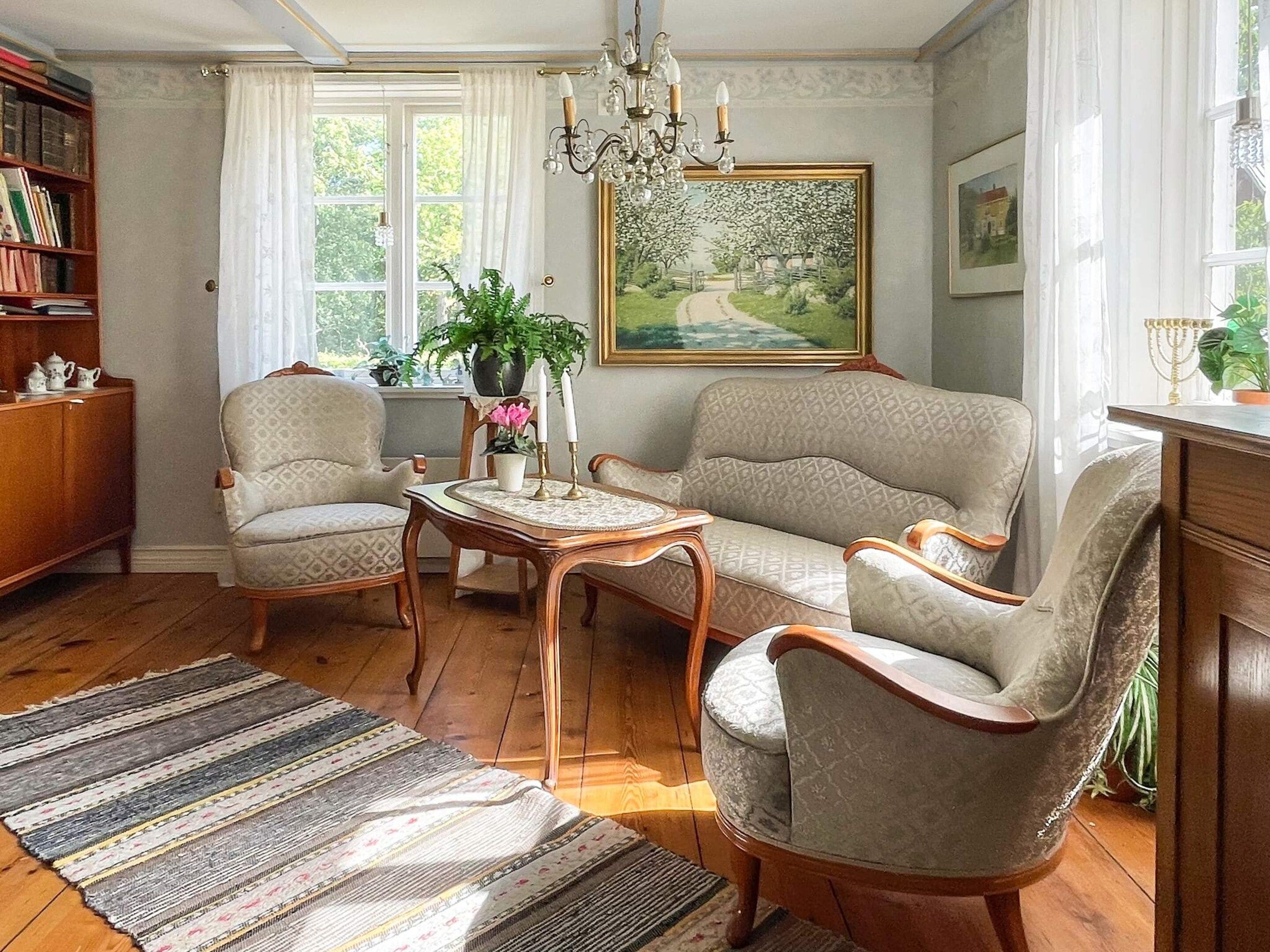 Ein traditionell eingerichtetes Wohnzimmer mit einer Sofagarnitur, einem Holztisch und einer Deckenleuchte.