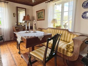 Une pièce à l’ambiance traditionnelle, avec une table en bois, un banc rembourré et une table à manger recouverte d’une nappe en dentelle.