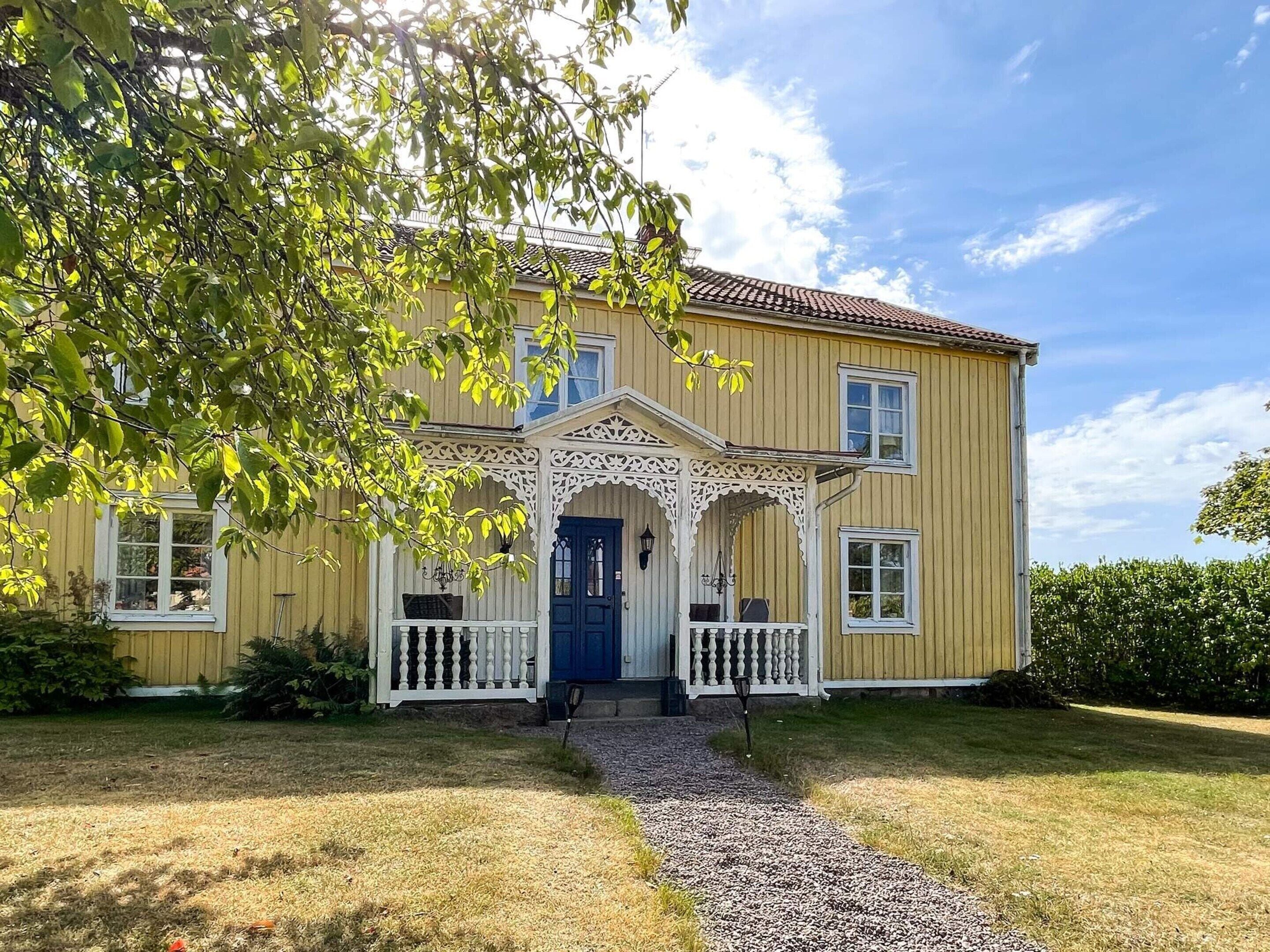 A two-story house with a porch, a front door, and a pathway leading to the entrance.
