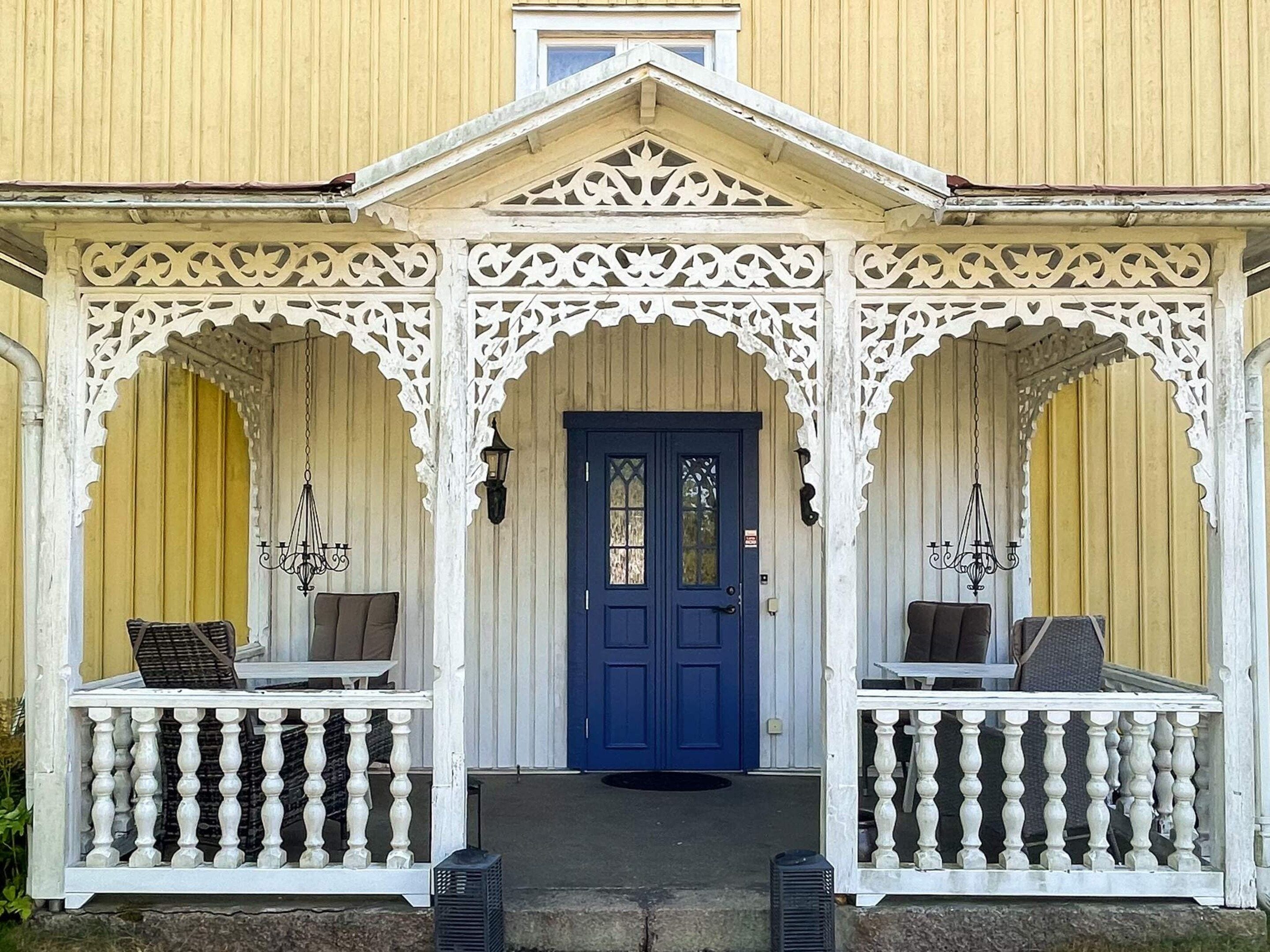 En bygning med en blå dør, hvide gelændere og en veranda med to borde og stole.