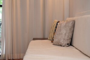 A bed with a white mattress and two pillows, one with a geometric pattern, in a room with sheer curtains. - Central Apartment in the Hotel Zone, 10 Minutes from the Boardwalk (Puerto Vallarta)