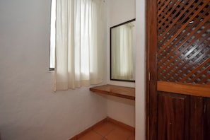 Ein Zimmer mit Fenster, Spiegel und einer Holztür mit Gitterwerk.