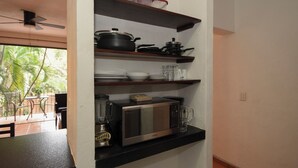 Una cocina con microondas, licuadora y estantes con utensilios de cocina.