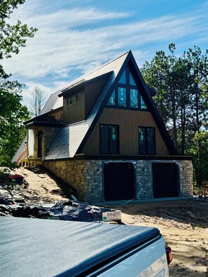 A modern house with a stone foundation, a sloped roof, and a garage.