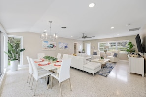 A modern kitchen with white cabinetry, a dining area with a white table and chairs, and a living room with a white sofa and a ceiling fan. - 4-Min Walk to Atlantic Ave | Hot Tub, Sleeps 6 (Delray Beach)