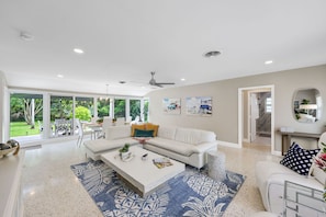 A spacious living room with a white sofa, a coffee table, and artwork on the walls. - 4-Min Walk to Atlantic Ave | Hot Tub, Sleeps 6 (Delray Beach)
