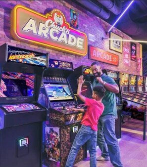 A gaming arcade with neon signs, including 'Arcade' and 'Asteroids,' and various arcade machines. - Magical 2BR Getaway at Westgate Town Minutes from Disney and All Theme Parks (Kissimmee)