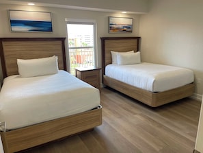 A hotel room with two wooden beds, a nightstand, a window with a view, and two wall-mounted paintings. - Magical 2BR Getaway at Westgate Town Minutes from Disney and All Theme Parks (Kissimmee)