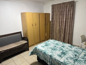 Un dormitorio con cama, armario, sofá y una silla.