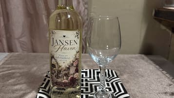 A bottle of Jansen Haven wine and an empty glass on a patterned tablecloth.