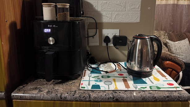 Una cocina con cafetera, hervidor y una encimera con un mantel individual.