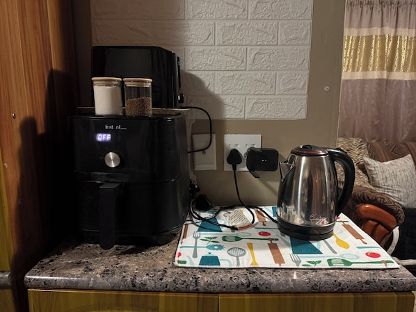 Una cocina con cafetera, hervidor y una encimera con un mantel individual.