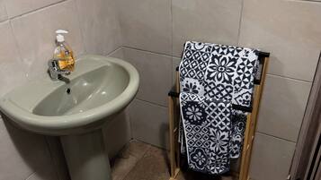 Ein Badezimmer mit einem Waschbecken, einem Handtuchhalter mit einem gemusterten Handtuch und einer grünen Matte auf dem Boden.