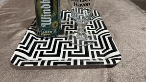 Una lata de cerveza Jansen Haven y un vaso sobre un mantel estampado.