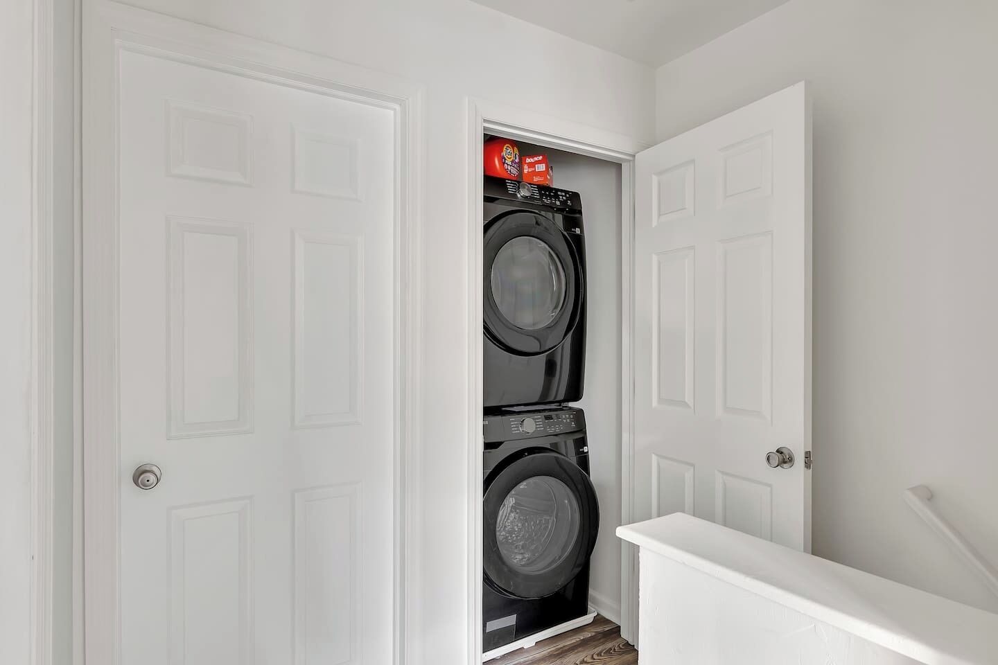 A laundry room with two stacked washing machines and a white door.