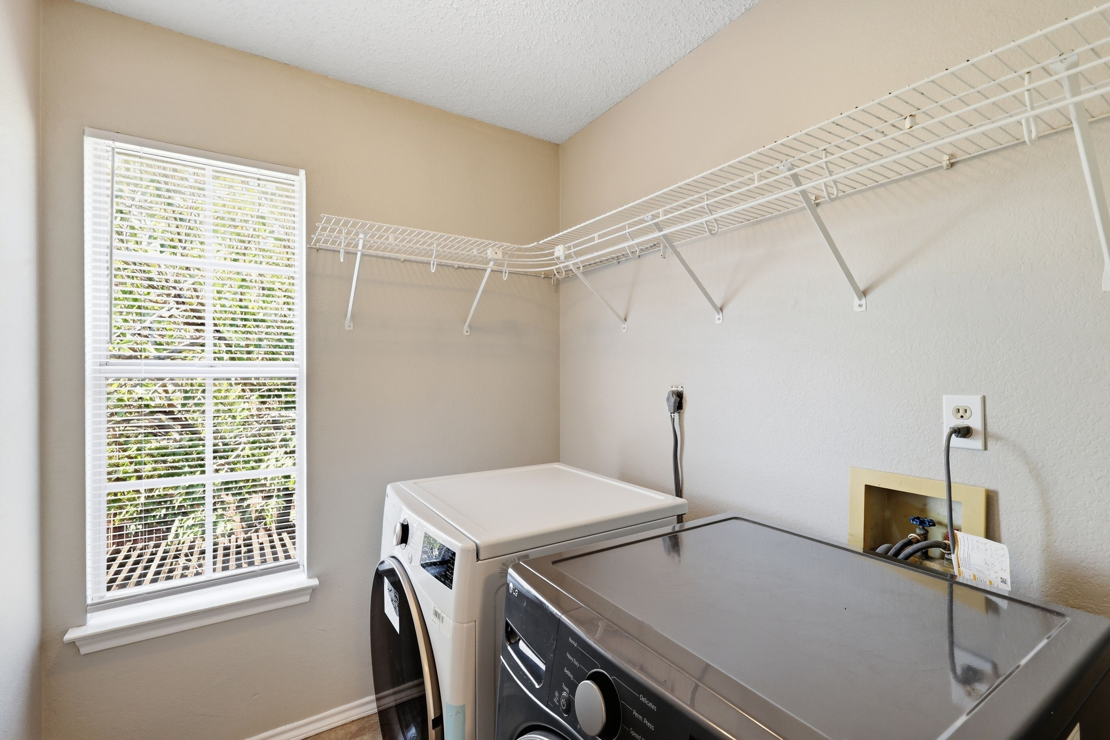 A laundry room with a washing machine, dryer, and a drying rack.