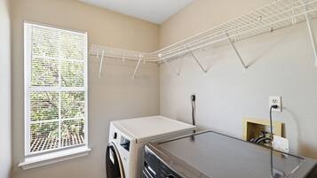 A laundry room with a washing machine, dryer, and a drying rack.
