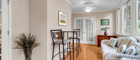 A spacious room with a dining area, a sofa set, and a ceiling fan.