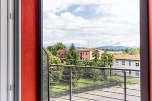 Een balkon met een metalen hekwerk met uitzicht op een woonwijk met huizen en bomen.
