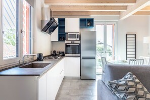 Een moderne keuken met een inbouwoven, magnetron en een koelkast van roestvrij staal.