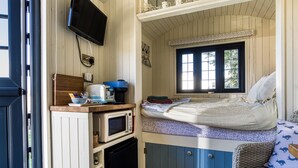 Una habitación funcional con cama, kitchenette, televisión y ventana.