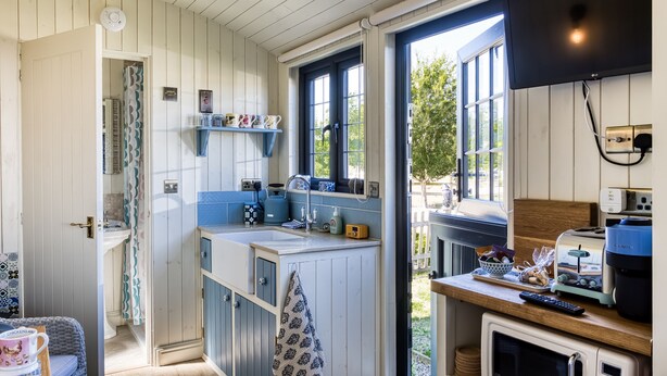 Una cocina con ventana, microondas y lavamanos.