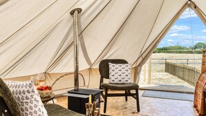 Ein Zeltinnenraum mit einer Sitzecke, einem Tisch mit Getränken und Früchten sowie Blick ins Freie.