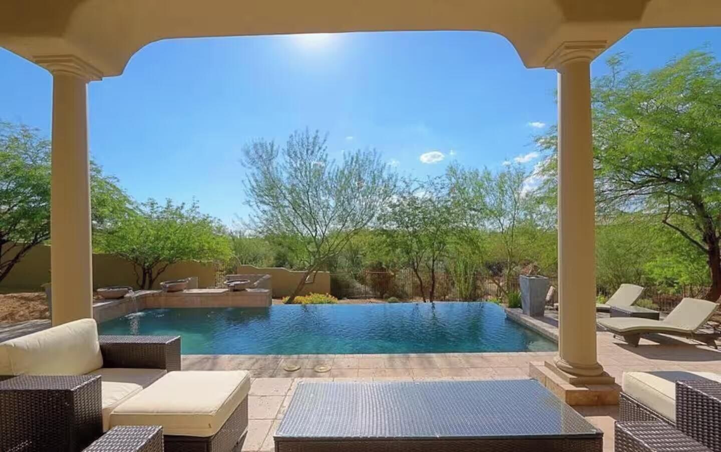 Un espace piscine doté de chaises longues et d’une pergola.
