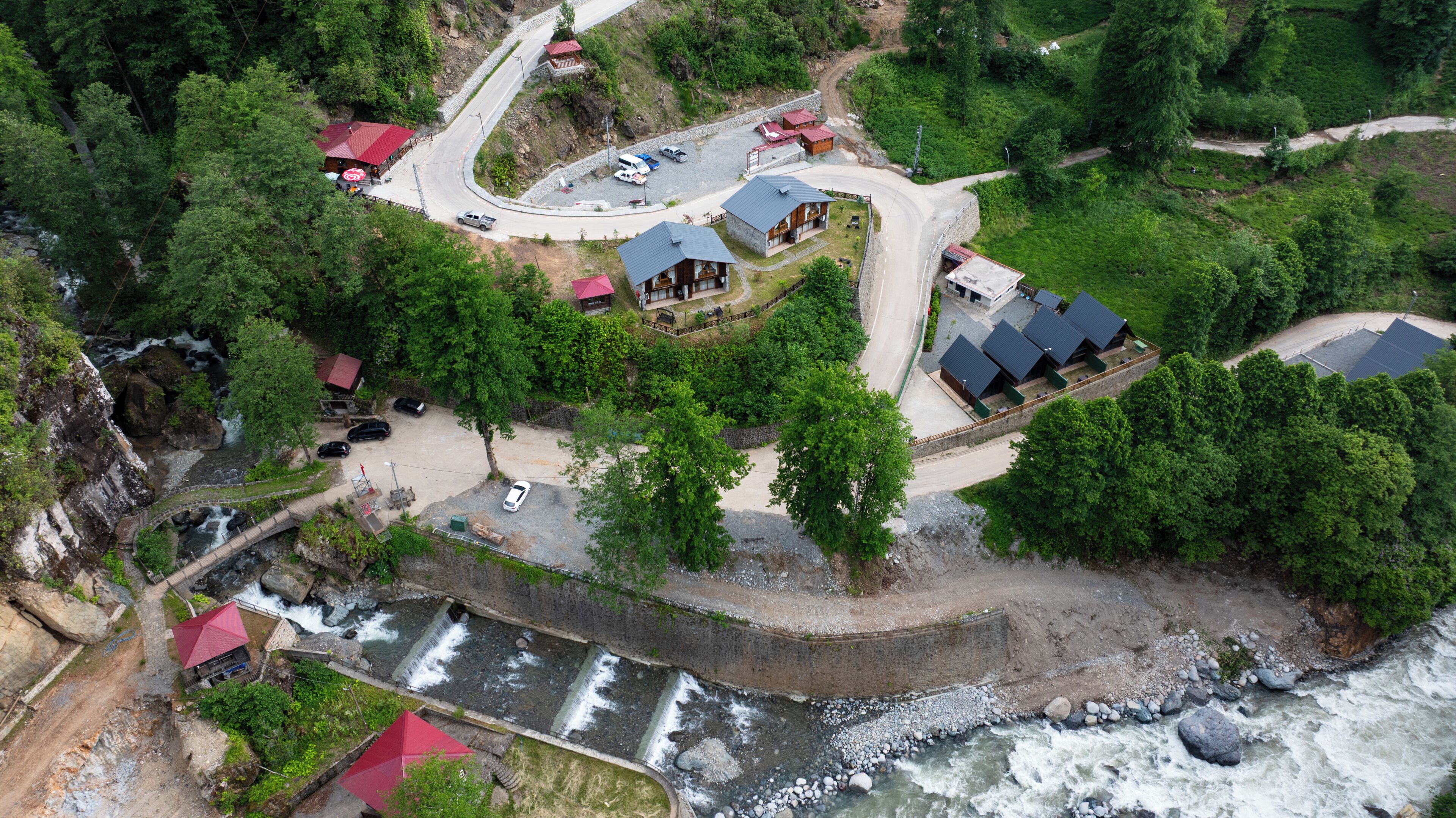 An aerial view of a resort with multiple buildings, a winding road, and a river.