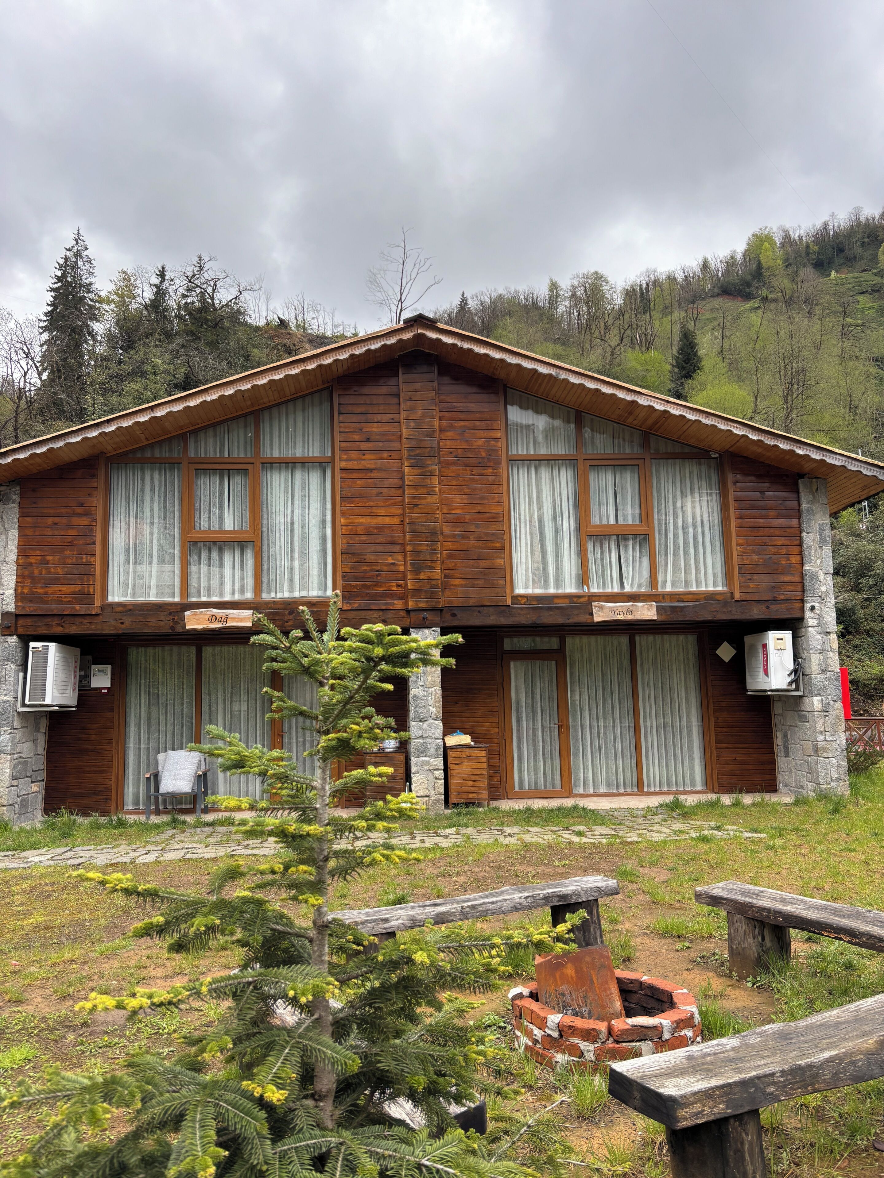 A wooden cabin with a stone foundation, large windows, and a small porch area.