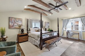 Ein Schlafzimmer mit einem Himmelbett, einer Bank, einem Schreibtisch und einem Stuhl.