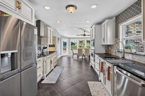 A modern kitchen with stainless steel appliances, white cabinetry, and a view to the outdoors. - Lake & Lark House-4BR Lakefront Retreat Downtown (Orlando)