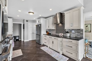 A modern kitchen with white cabinetry, stainless steel appliances, and a patterned rug. - Lake & Lark House-4BR Lakefront Retreat Downtown (Orlando)