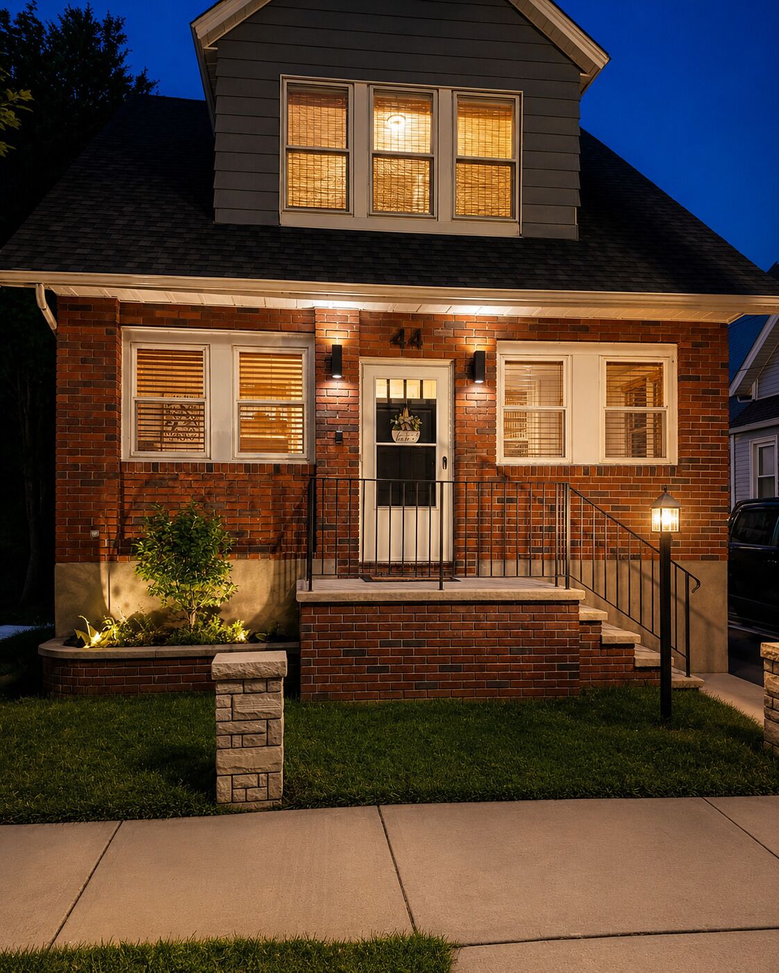 A two-story house with a brick facade, a front porch, and a well-lit entrance.