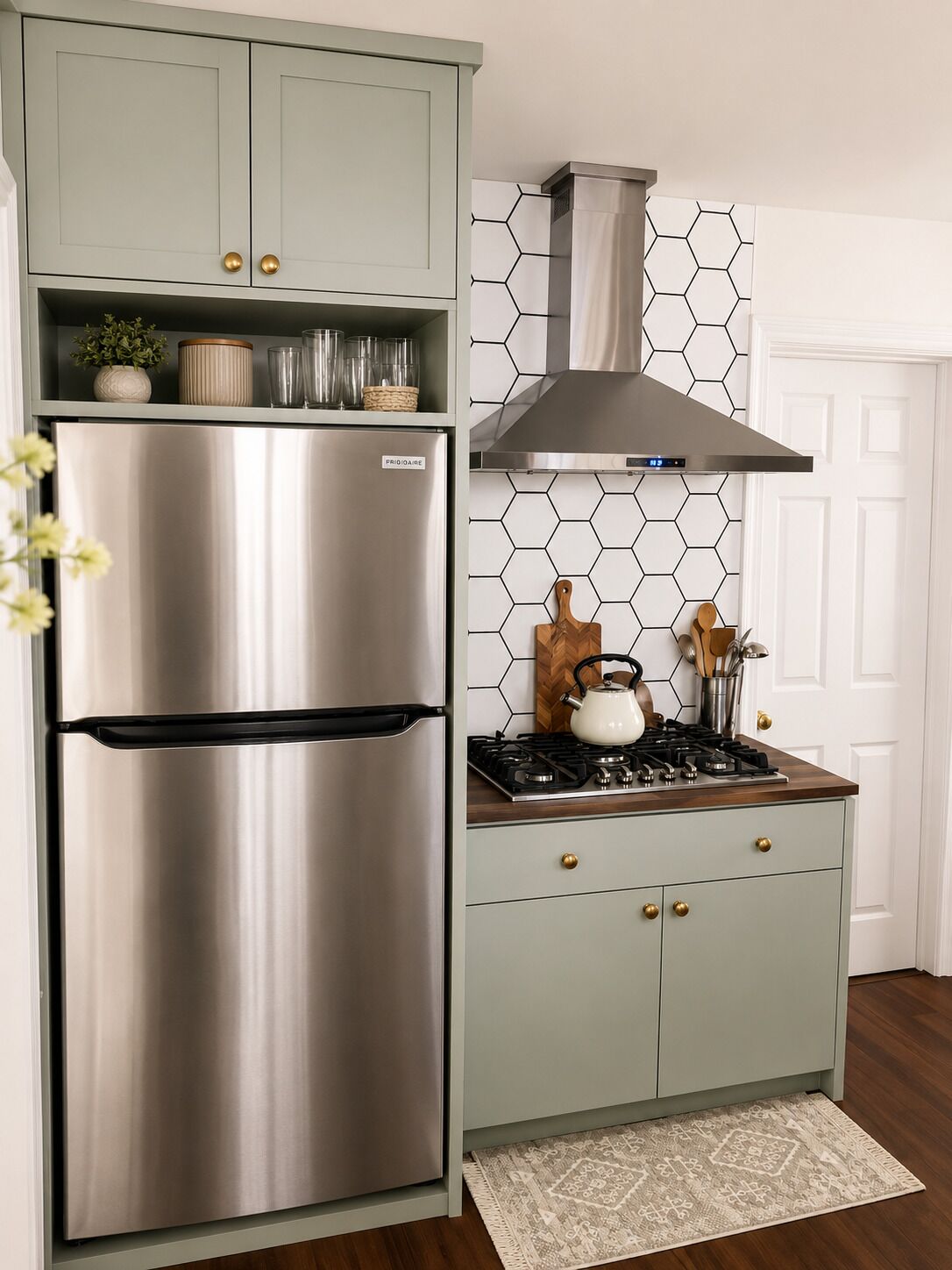 A kitchen with a stainless steel refrigerator, a gas stove, and a hexagonal patterned backsplash.