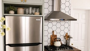 Una cocina con un refrigerador de acero inoxidable, una estufa a gas y un salpicadero con diseño hexagonal.