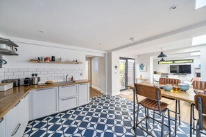 A modern kitchen with white cabinets, a wooden countertop, and a patterned floor. - Coach House Retreat - Beaminster, Dorset (Beaminster)