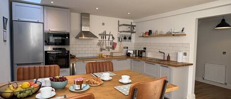 Una cocina moderna con comedor, equipada con electrodomésticos de acero inoxidable, encimeras de madera y un piso con estampado geométrico.