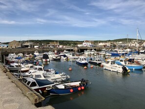 A marina with various boats docked, a stone wall, and buildings in the background. - Coach House Retreat - Beaminster, Dorset (Beaminster)