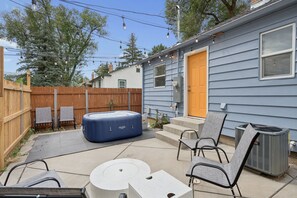 A backyard with a hot tub, outdoor furniture, and a house with a blue siding exterior. - Downtown 2 bedroom ranch home with hot tub, AC and all the amenities! (Colorado Springs)