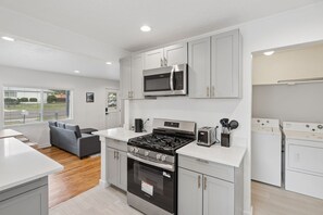 A modern kitchen with stainless steel appliances, grey cabinetry, and a built-in oven. - Downtown 2 bedroom ranch home with hot tub, AC and all the amenities! (Colorado Springs)