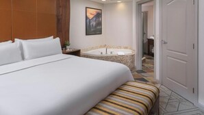 A hotel room with a large bed, a bathtub, and a door leading to another room. - Sheraton Mountain Vista 1 BR (Avon)